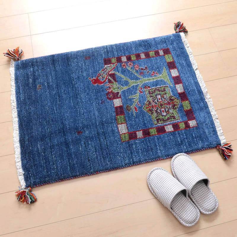 青の手織りギャッベラグが木目調の床に敷かれ、ペルシャ絨毯のような美しい模様が際立っています。