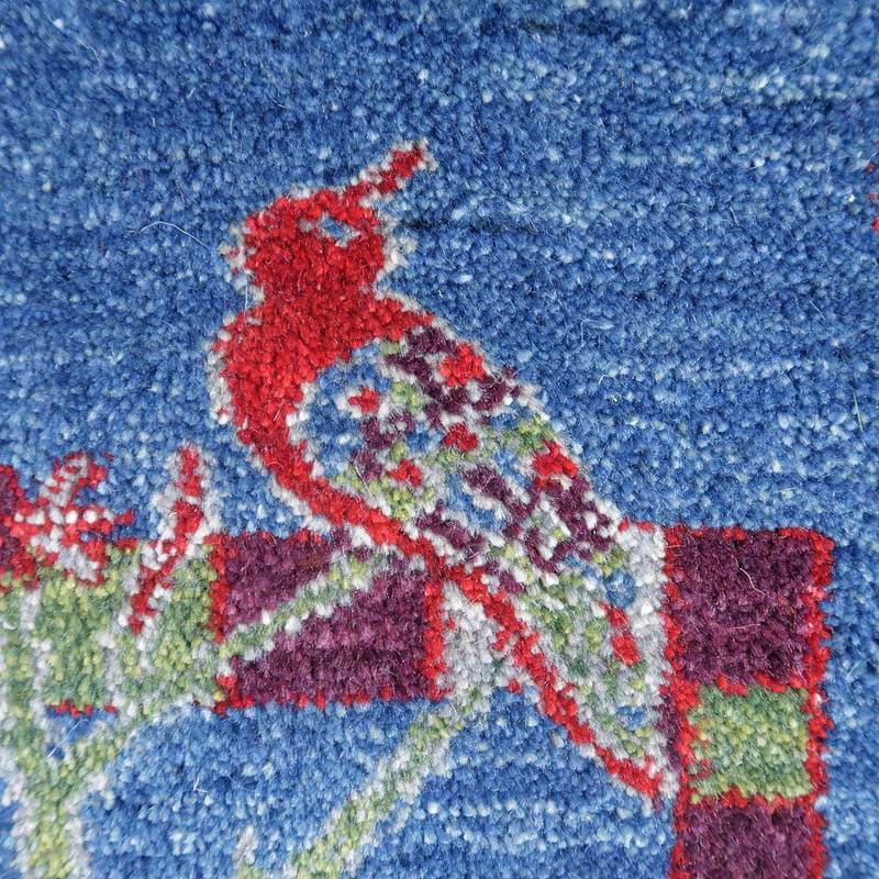 青い背景に赤い鳥が織り込まれた手織りのギャッベラグが、ウールの素材感と共に鮮やかに際立っている。