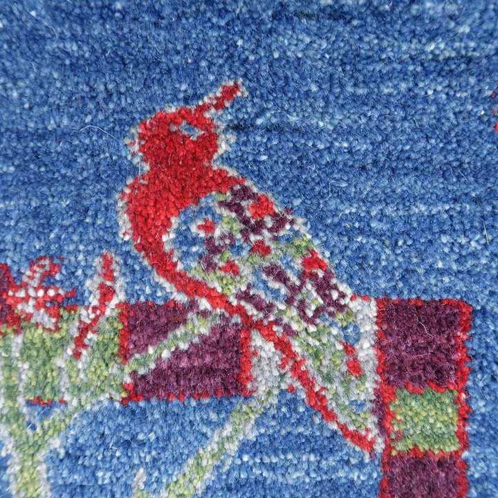 青い背景に赤い鳥が織り込まれた手織りのギャッベラグが、ウールの素材感と共に鮮やかに際立っている。