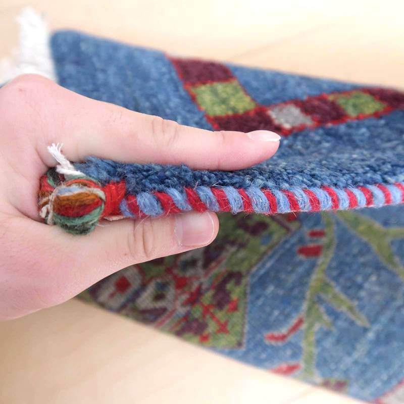 手織りのギャッベラグの厚みと織り目が際立つ接写で、青と赤のウール素材が丁寧に編み込まれている様子が見える。