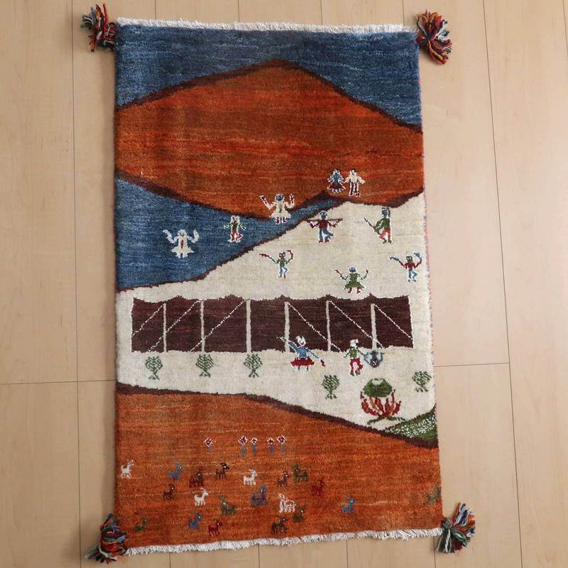 ギャッベ／ルリバフ 91×56cm（HSS-71853）は、色鮮やかなオレンジと青の地にペルシャ絨毯の伝統模様が丁寧に手織りされたギャッベラグが床に広がり、温かみが感じられます。