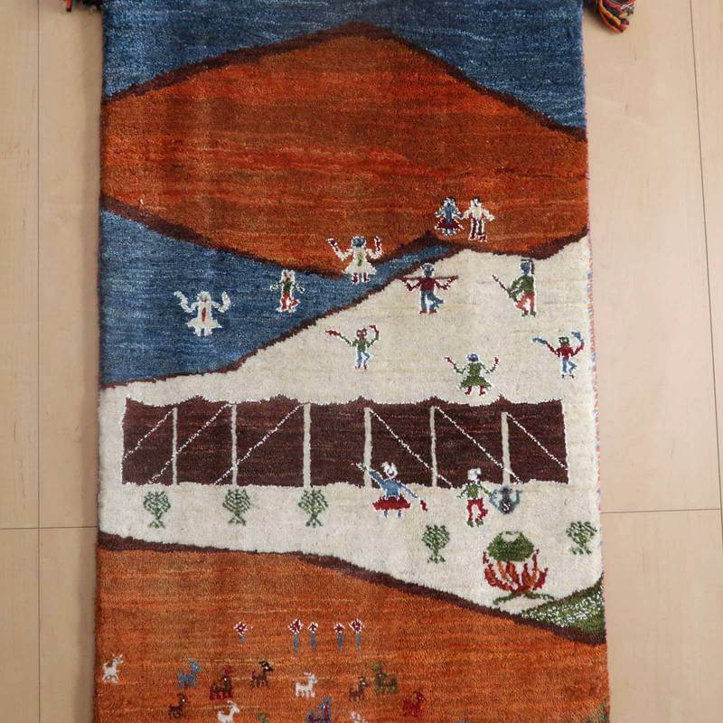 色彩豊かなペルシャ絨毯のギャッベラグが、手織りのぬくもりを感じさせるデザインで床に敷かれている。