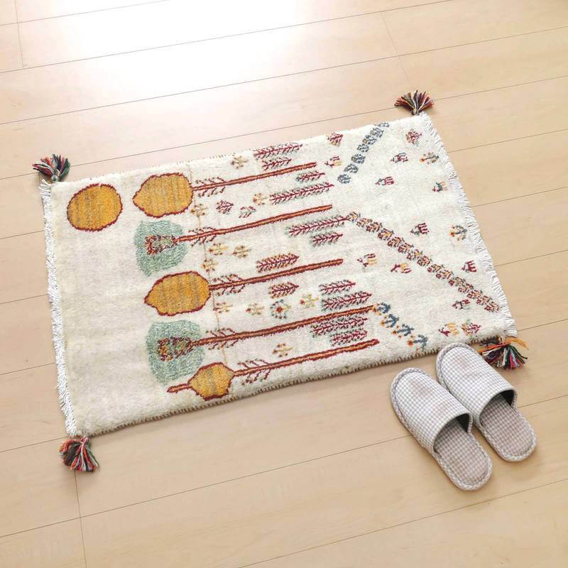 白い床の上に、温かみのある色合いの手織りギャッベラグが美しく敷かれている。