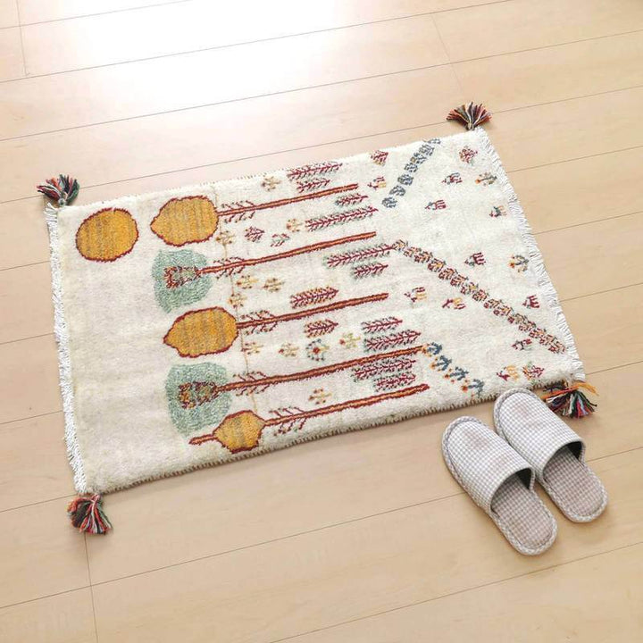白い床の上に、温かみのある色合いの手織りギャッベラグが美しく敷かれている。