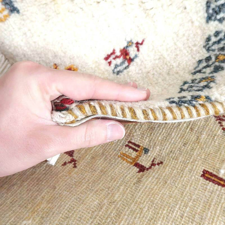 ぬくもりあるペルシャ絨毯のギャッベラグが手織りのウール素材で丁寧に編み込まれた厚みを感じる様子が見える。