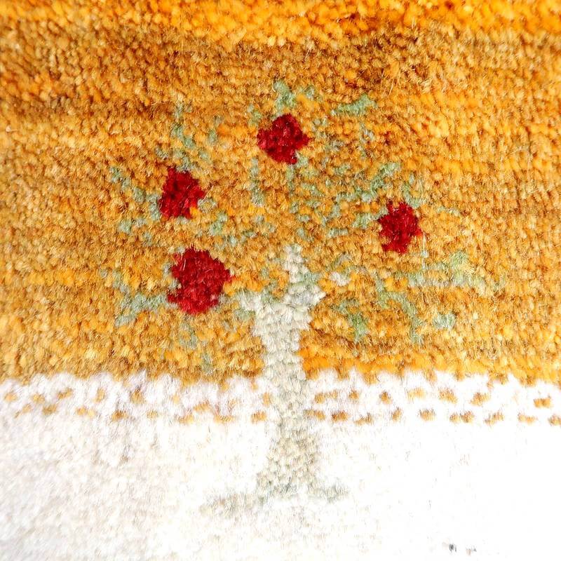 手織りのギャッベラグで、温かみのあるオレンジ色の背景に赤い花柄が丁寧に織り込まれたデザインが際立つウール素材の一部が見える。