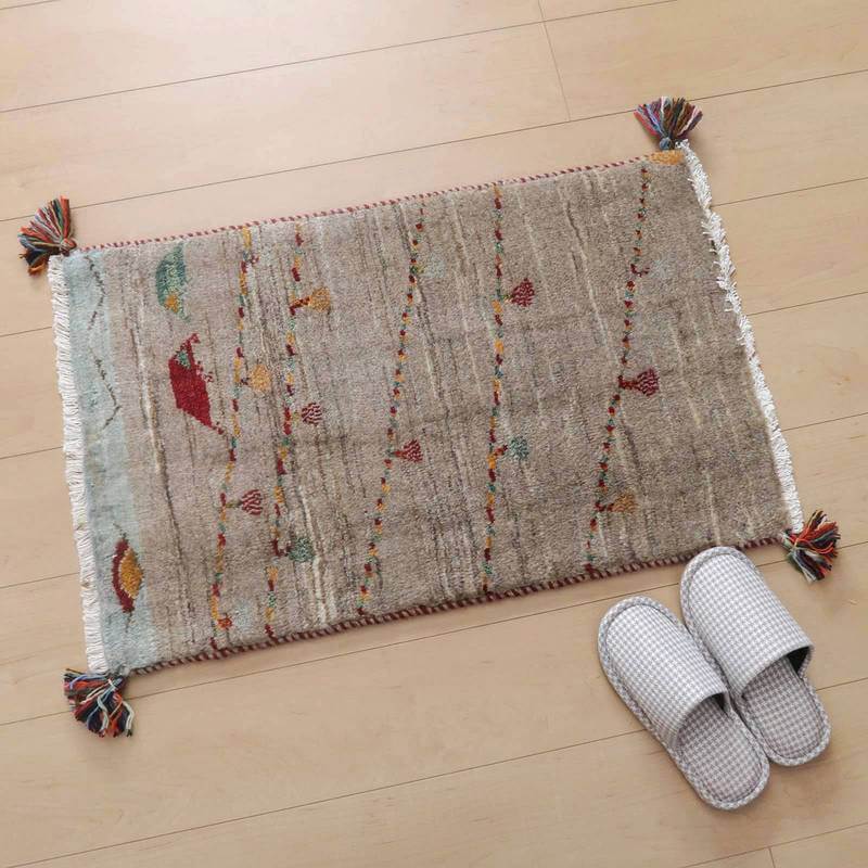 手織りのウール製ギャッベラグが玄関に敷かれ、繊細なペルシャ絨毯の模様が木製の床に映えています。