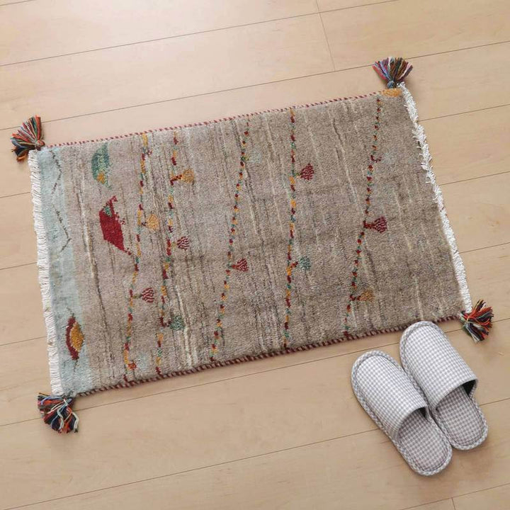 手織りのウール製ギャッベラグが玄関に敷かれ、繊細なペルシャ絨毯の模様が木製の床に映えています。