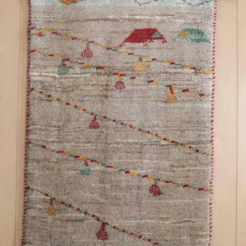 手織りのウールを使用したギャッベラグが、ペルシャ絨毯専門店の通販で提供され、床に温かみのある模様が広がっています。