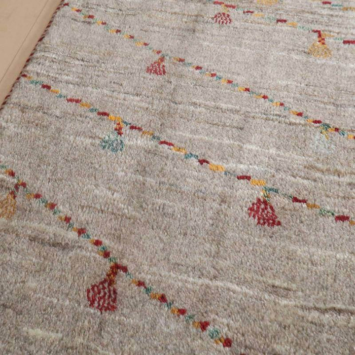 手織りのペルシャ絨毯専門店からのウール製ギャッベラグが、色鮮やかな模様で床に敷かれている。