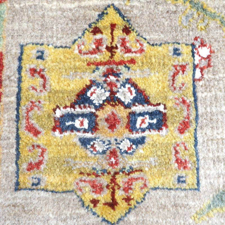 丁寧に手織りされたウールのギャッベラグの接写で、鮮やかな黄色と赤のペルシャ絨毯模様が豊かに際立っている。