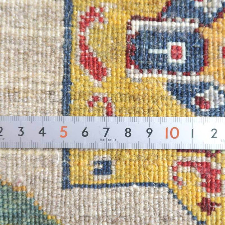 定規でサイズが計測された手織りのギャッベラグは、ウール素材の色鮮やかな模様が際立ち、専門店通販で手に入る。