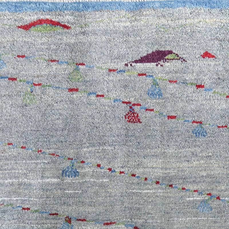 手織りのギャッベラグが、グレーの背景にカラフルな模様が浮かび上がり、繊細なウールの質感が際立っている。