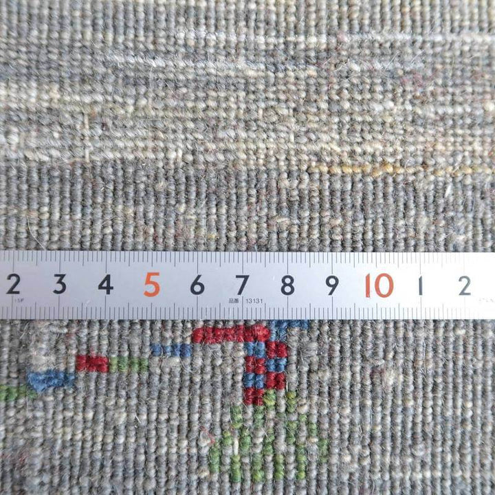 手織りのウール製ギャッベラグの織り密度を定規で測定しており、専門店通販で人気のペルシャ絨毯の細やかな模様が際立っています。