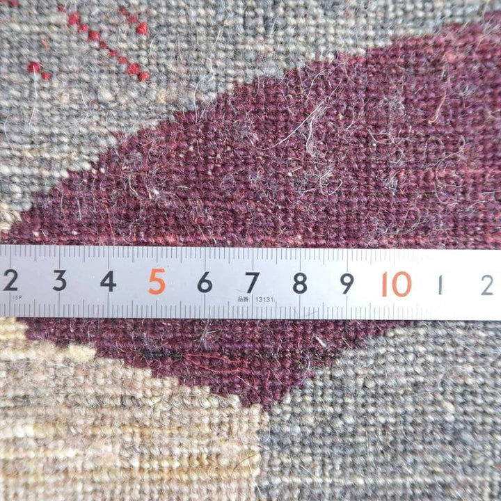 手織りのギャッベラグのウール素材が持つ温かみを、ペルシャ絨毯専門店の通販用に、定規でその織りの密度が正確に示されている。