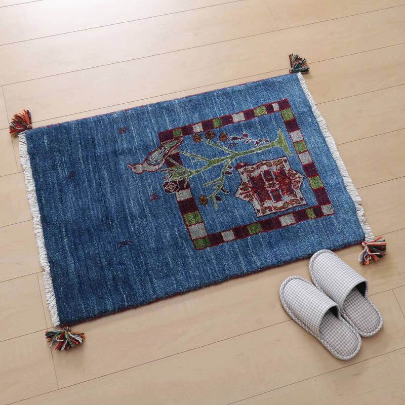 青いウールのギャッベラグが、ペルシャ絨毯専門店の通販で提供され、木目調の床にぬくもりを添えている。