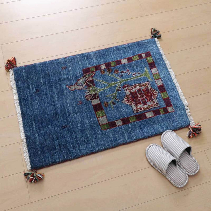 青いウールのギャッベラグが、ペルシャ絨毯専門店の通販で提供され、木目調の床にぬくもりを添えている。