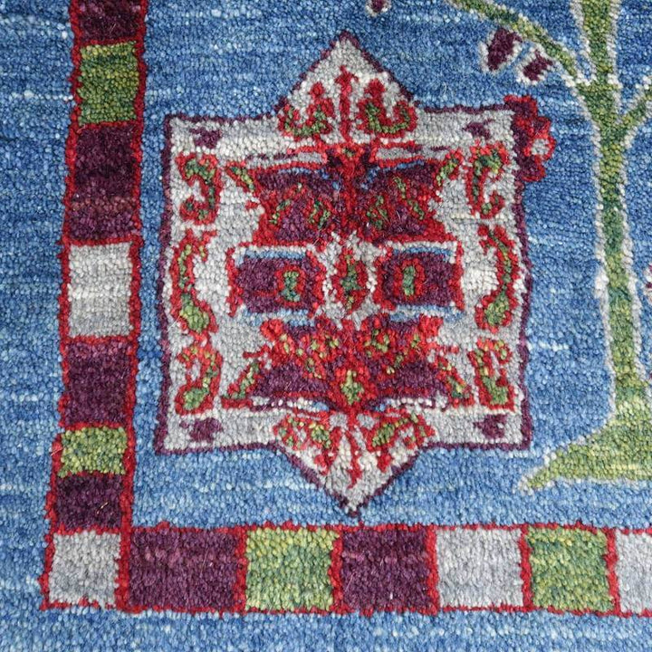 鮮やかな青地に繊細な赤と緑の模様が丁寧に手織りされたウールのギャッベラグが見える。