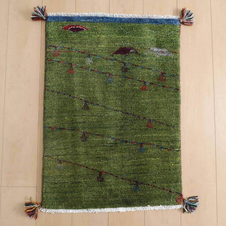 ギャッベ／ルリバフ 83×60cm（HSS-72502）は、緑のウールで丁寧に手織りされたギャッベラグが、ペルシャ絨毯の専門店から通販で購入でき、床に敷かれている。