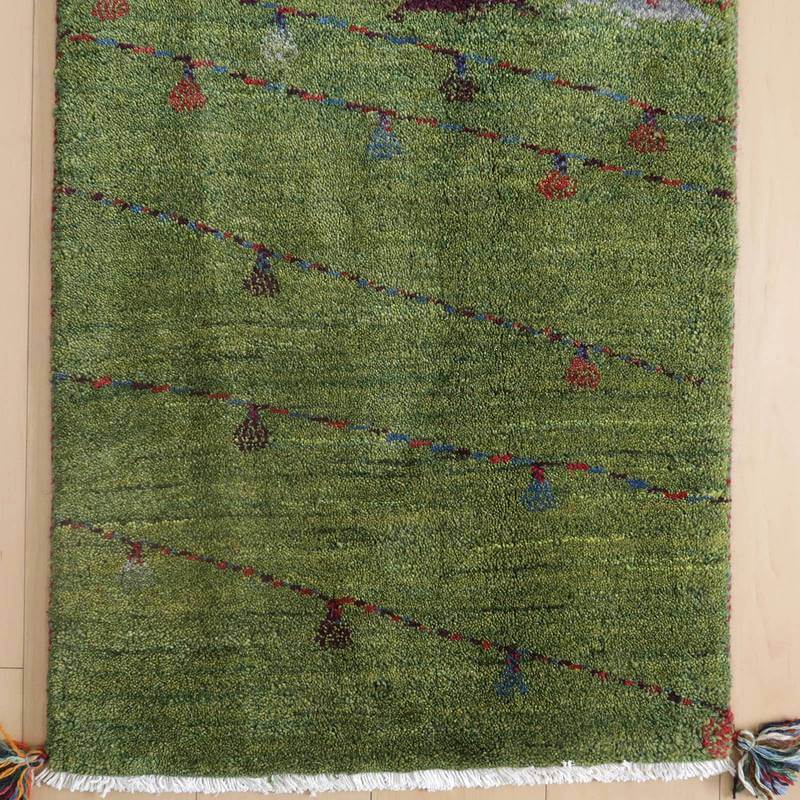 緑豊かなウールの手織りギャッベラグが、斜めに走る色鮮やかなラインと小さなモチーフで玄関を華やかに演出している。
