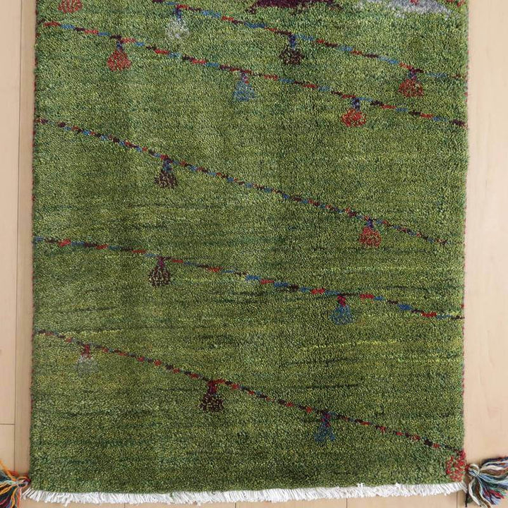 緑豊かなウールの手織りギャッベラグが、斜めに走る色鮮やかなラインと小さなモチーフで玄関を華やかに演出している。