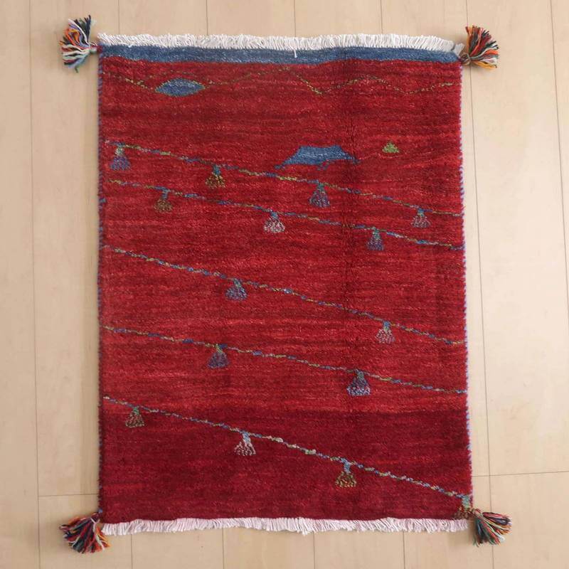 ギャッベ／ルリバフ 80×62cm（HSS-72549）は、鮮やかな赤と独特の模様が美しいペルシャ絨毯のギャッベラグが、ウールの温かみを感じさせる手織りの風合いで床に敷かれている。