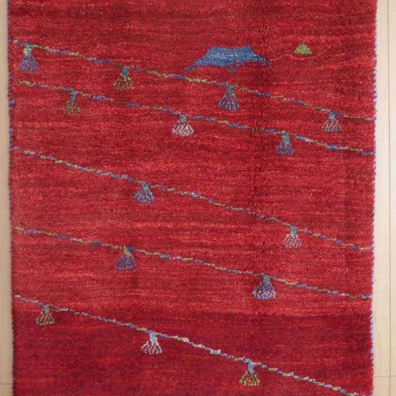 赤を基調にしたペルシャ絨毯の手織りギャッベラグが、カラフルな模様とともに床に広がっている。