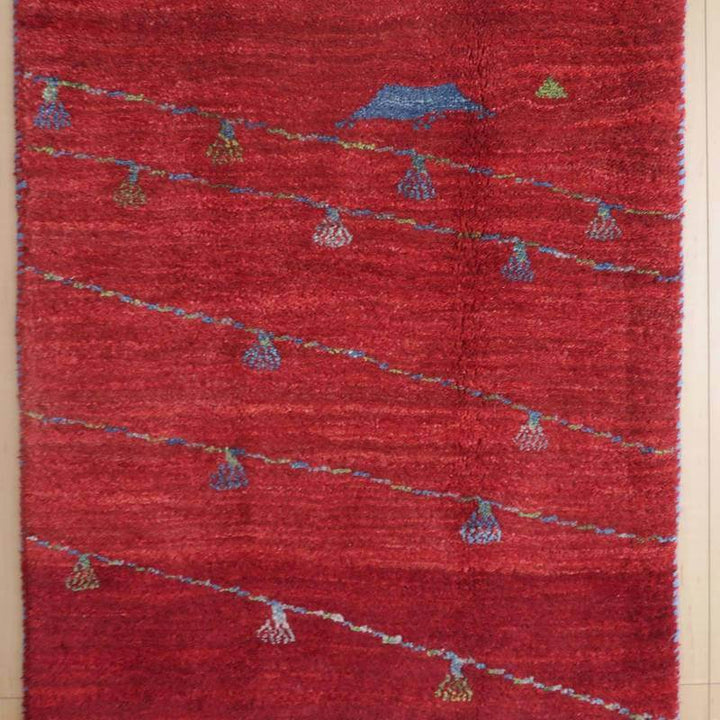 赤を基調にしたペルシャ絨毯の手織りギャッベラグが、カラフルな模様とともに床に広がっている。