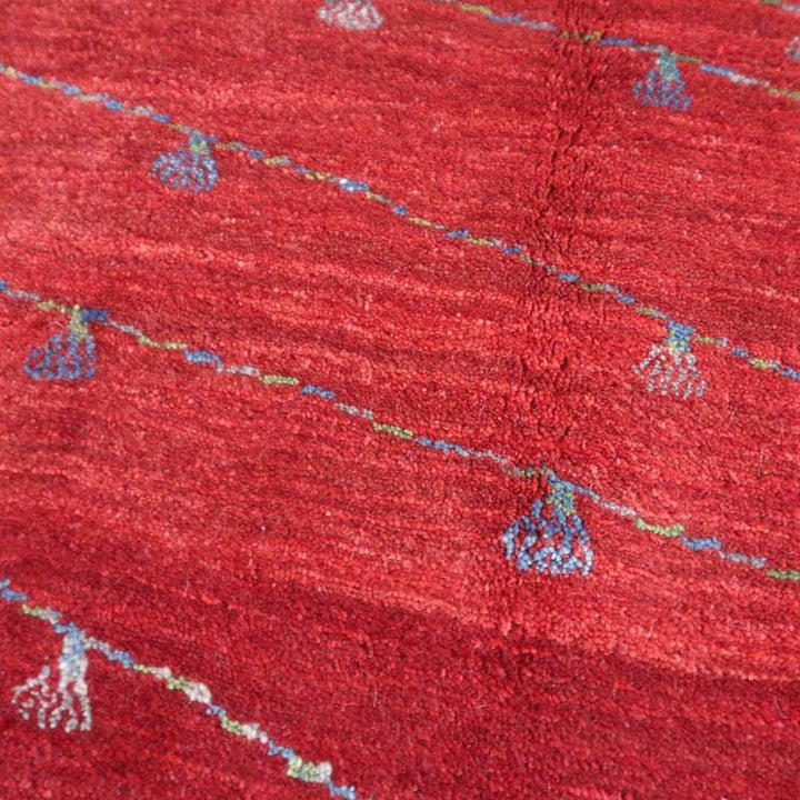 深い赤色と繊細な模様が魅力的な手織りのギャッベラグは、ウール素材の温かみが感じられ、ペルシャ絨毯専門店の通販で購入できる。