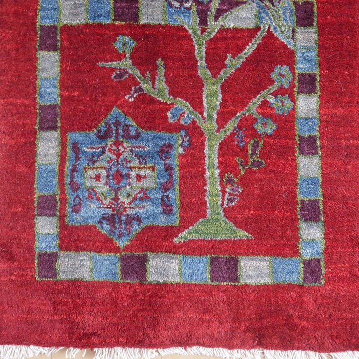 赤を基調にした手織りのギャッベラグは、ペルシャ絨毯専門店で通販可能な美しいウール素材のデザインが床に華やかに広がっている。