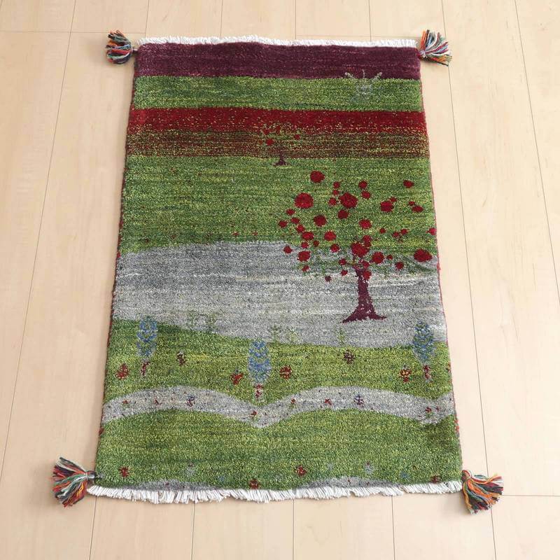 ギャッベ／ルリバフ 87×57cm（HSS-72575）は、緑と赤の織り模様が美しい手織りのギャッベラグが床に敷かれており、ペルシャ絨毯専門店で通販可能なウール素材の温かみが感じられます。