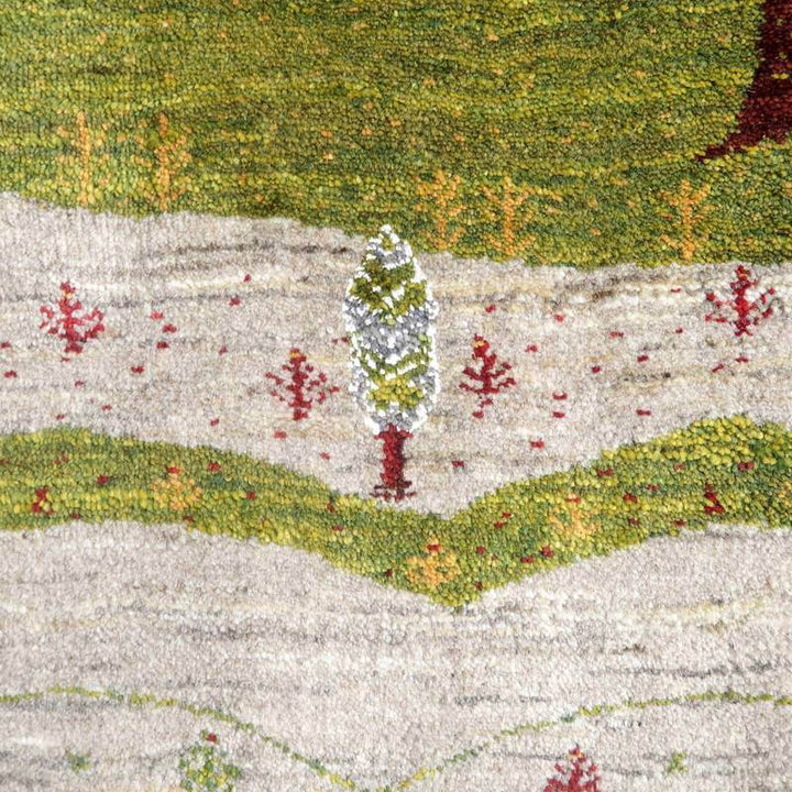 手織りのギャッベラグが、緑豊かな自然の風景を繊細に表現し、ウールの柔らかさと色彩が調和している。