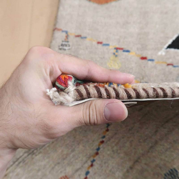 手織りのギャッベラグの厚みと密度を示すウールの質感が際立つ一枚で、色鮮やかな模様が垣間見える。