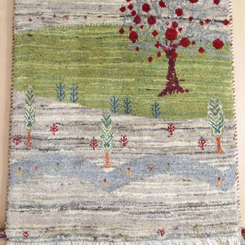 緑豊かな風景と赤い花が丁寧に手織りされたウールのギャッベラグが、ペルシャ絨毯の専門店通販で見つかる。