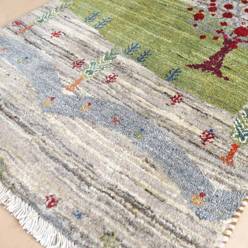 手織りのギャッベラグが優雅に広がり、緑豊かなペルシャ絨毯の模様が丁寧に織り込まれている。