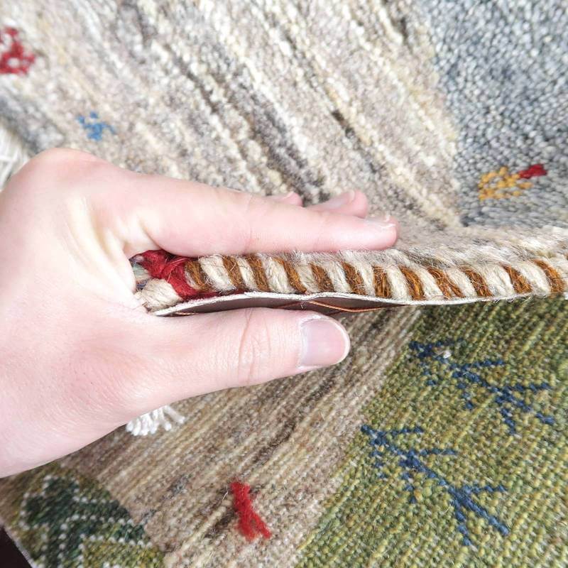 手織りのウール製ギャッベラグが持ち上げられ、ペルシャ絨毯専門店の通販で購入可能な厚みと織りの密度が際立っています。