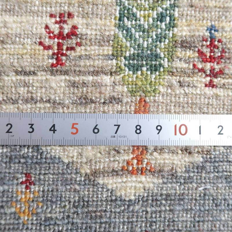 手織りのギャッベラグの織り目が細かく、ウールの質感が際立つペルシャ絨毯専門店の通販商品が定規と共に見える。