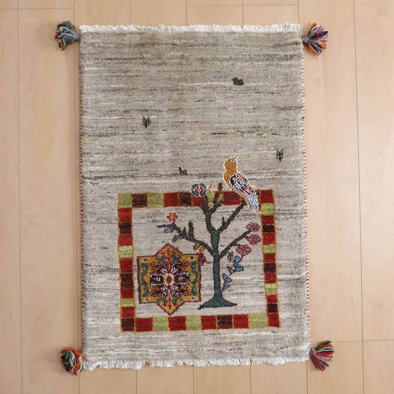 ギャッベ／ルリバフ 87×60cm（HSS-73149）は、手織りのウールで作られたペルシャ絨毯のギャッベラグが床に広がり、色鮮やかな鳥と植物のデザインが織り目に際立っている。