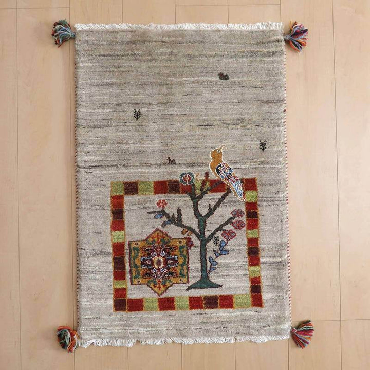 ギャッベ／ルリバフ 87×60cm（HSS-73149）は、手織りのウールで作られたペルシャ絨毯のギャッベラグが床に広がり、色鮮やかな鳥と植物のデザインが織り目に際立っている。