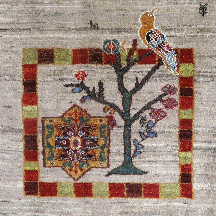 手織りのウール製ギャッベラグに描かれた鳥と木のモチーフが、ペルシャ絨毯の専門店で通販される逸品として際立っている。
