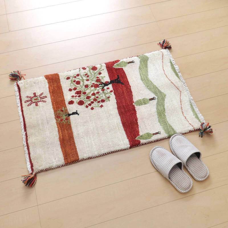 暖かみのある手織りのギャッベラグが木の模様と自然の色彩で床に広がり、ペルシャ絨毯専門店から通販可能なウールの織り目が際立っている。