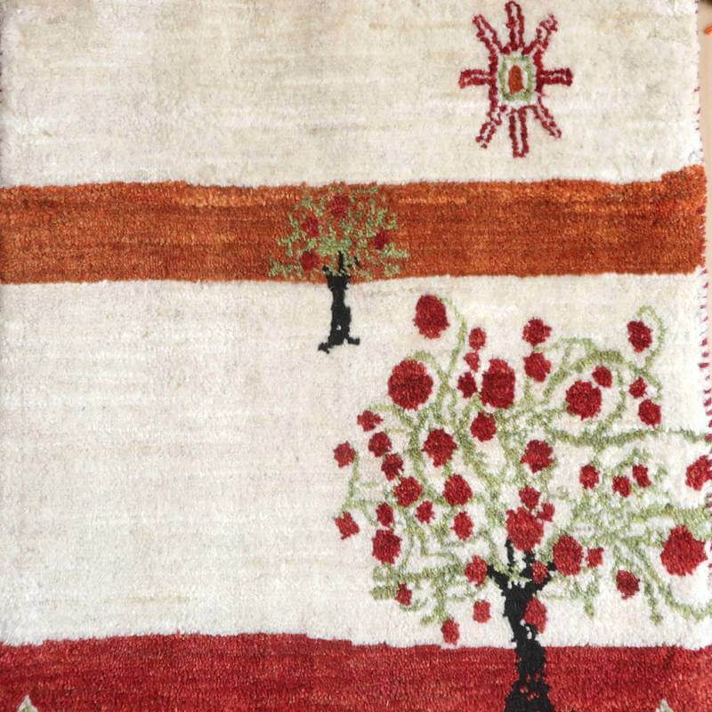 手織りのウールで丁寧に作られたギャッベラグは、赤い花と緑の木が印象的に描かれたデザインが特徴で、ペルシャ絨毯の専門店で通販されています。