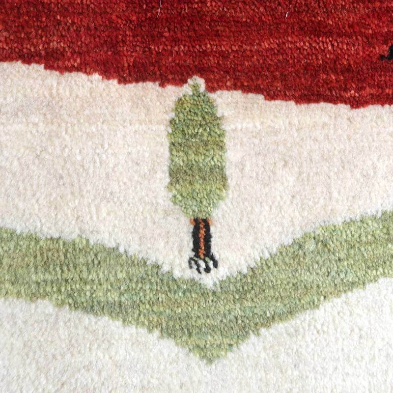 丁寧に手織りされたこのウール製ギャッベラグは、緑と赤のコントラストが美しく、小さな木のモチーフが温かみを添えている。