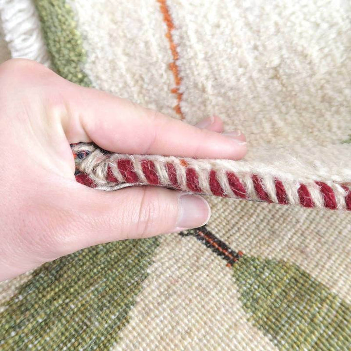 手織りで丁寧に仕上げられたペルシャ絨毯のラグが持ち上げられ、ウールの密な織り目と柔らかな厚みが際立っている。