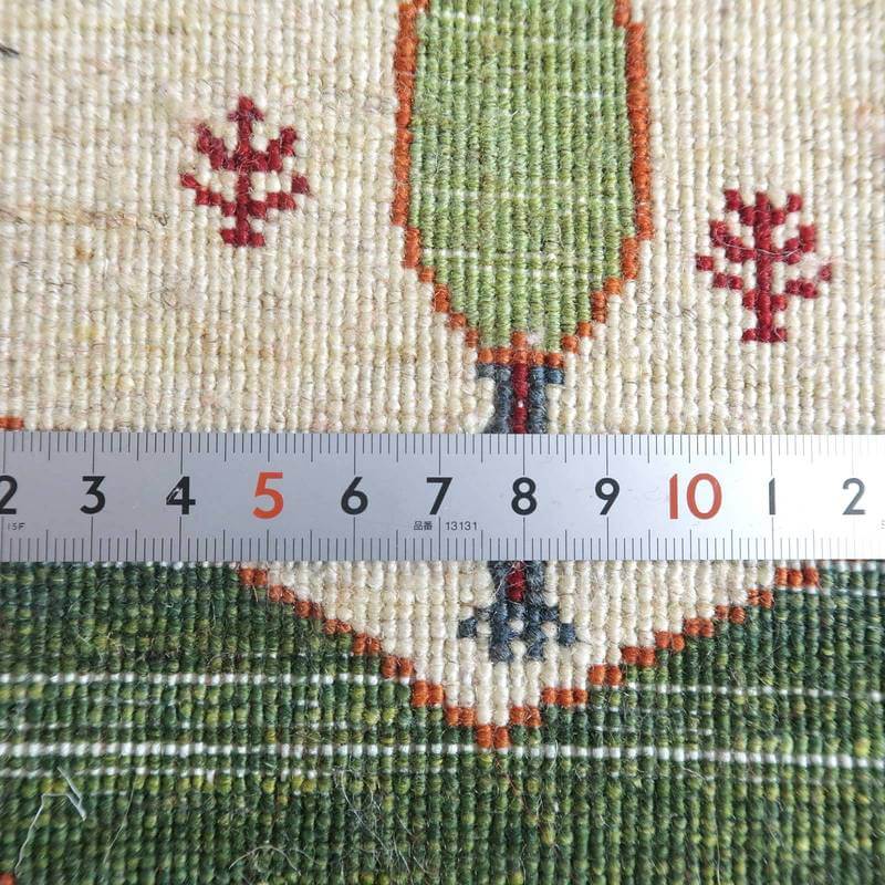 緻密に手織りされたウール素材のギャッベラグは、ペルシャ絨毯専門店の通販で購入でき、定規で測ることでその繊細な織り目が際立っている。