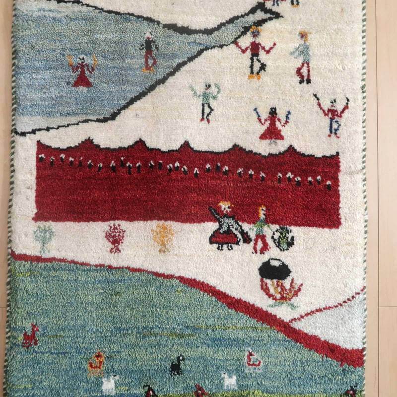 手織りのギャッベラグは、ペルシャ絨毯の伝統的な模様と温かみのあるウール素材が特徴で、通販専門店の床に色とりどりに敷かれている。