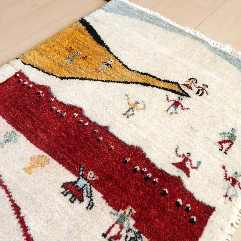 カラフルな模様が特徴の手織りギャッベラグが床に敷かれており、ペルシャ絨毯ならではの温かみが感じられるウール素材の質感が際立っている。