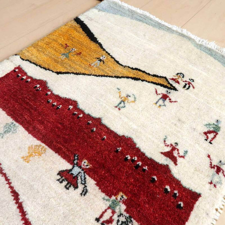 カラフルな模様が特徴の手織りギャッベラグが床に敷かれており、ペルシャ絨毯ならではの温かみが感じられるウール素材の質感が際立っている。