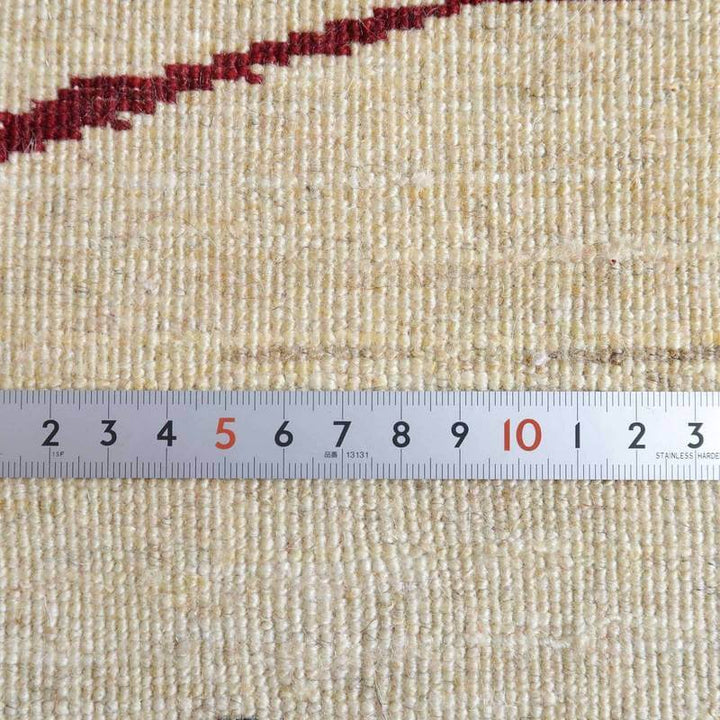 手織りウールのギャッベラグが定規と並び、ペルシャ絨毯の繊細な織り目と柔らかな質感が際立っている。