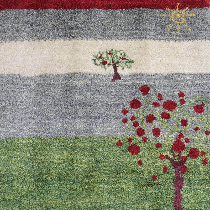 手織りウールのギャッベラグには、赤や緑の自然モチーフが施され、ぬくもりある風景が広がっている。